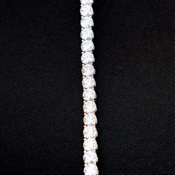 Diamond tennis bracelet on black background.