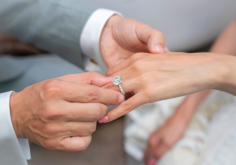 Person placing ring on another's finger.